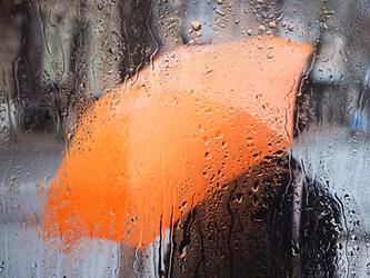 orange umbrella through rainy window